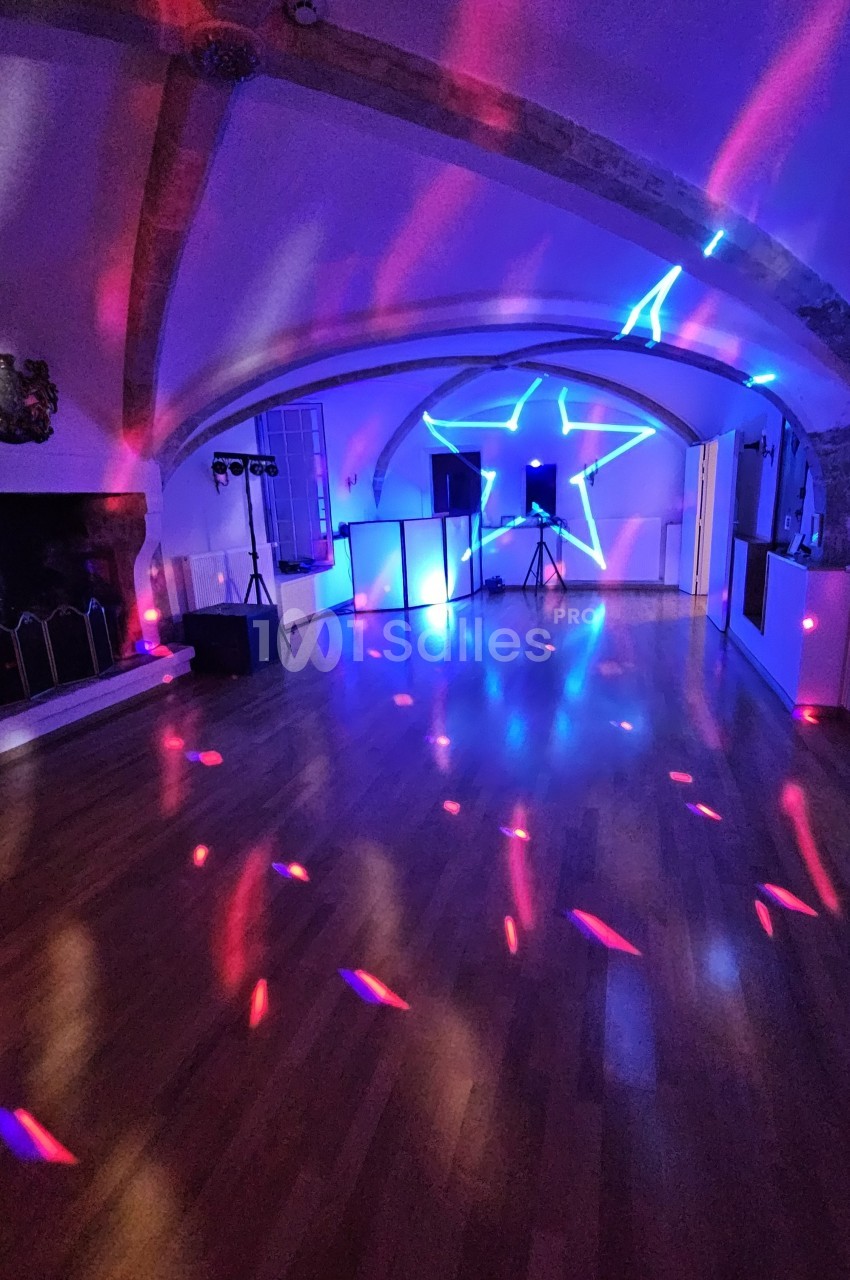 Salle avec éclairage coloré, projecteurs et étoile lumineuse sur un mur, ambiance festive sur parquet.