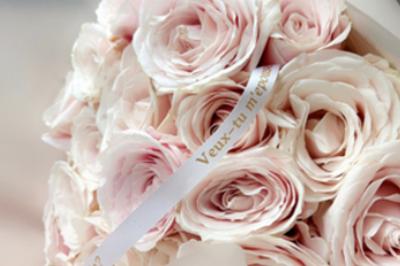 Une mariée en tailleur blanc tenant un bouquet devant une vitrine avec l'inscription ’Love Curated’.