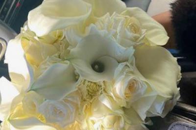 Une mariée en tailleur blanc tenant un bouquet devant une vitrine avec l'inscription ’Love Curated’.