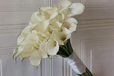 Une mariée en tailleur blanc tenant un bouquet devant une vitrine avec l'inscription ’Love Curated’.