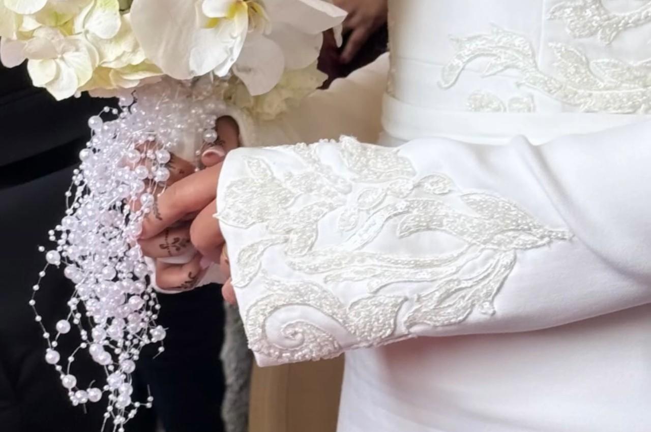 Une mariée en robe blanche tient un bouquet d'orchidées blanches avec des perles décoratives.