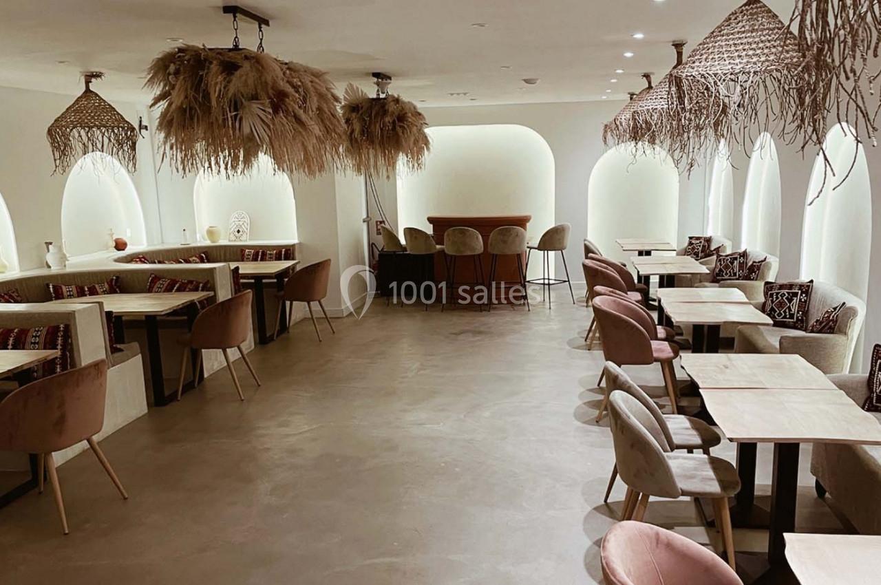 Salle de restaurant lumineuse avec mobilier en bois clair, chaises rembourrées et décorations suspendues naturelles.
