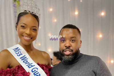Un DJ souriant derrière une table équipée de matériel audio, avec un ordinateur portable et une table de mixage.