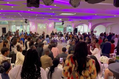 Un DJ souriant derrière une table équipée de matériel audio, avec un ordinateur portable et une table de mixage.