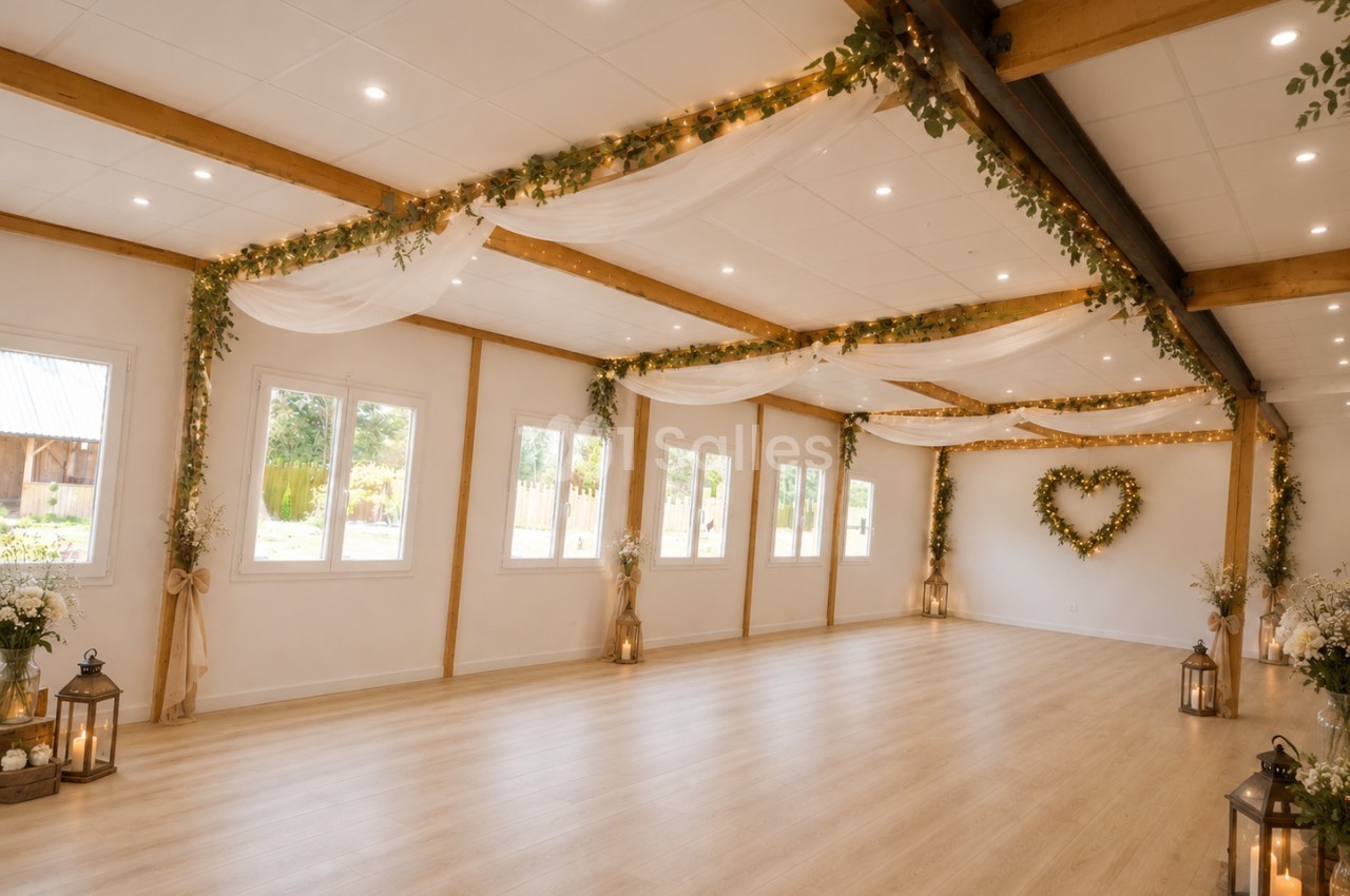 Salle intérieur spacieuse avec parquet clair, poutres en bois, décoration florale et guirlandes, baies vitrées donnant sur jardin.