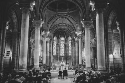 Un homme en costume bleu se tient debout sur une terrasse extérieure par temps nuageux.