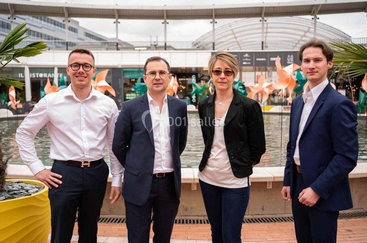 Quatre personnes posant devant une fontaine dans un espace extérieur urbain avec des décorations colorées.