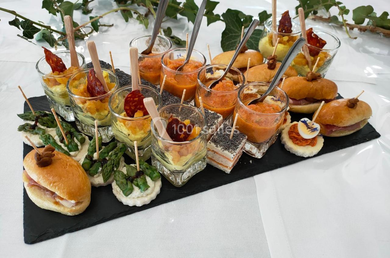 Plateau de bouchées apéritives variées comprenant verrines, mini-sandwichs et amuse-bouches sur ardoise noire.
