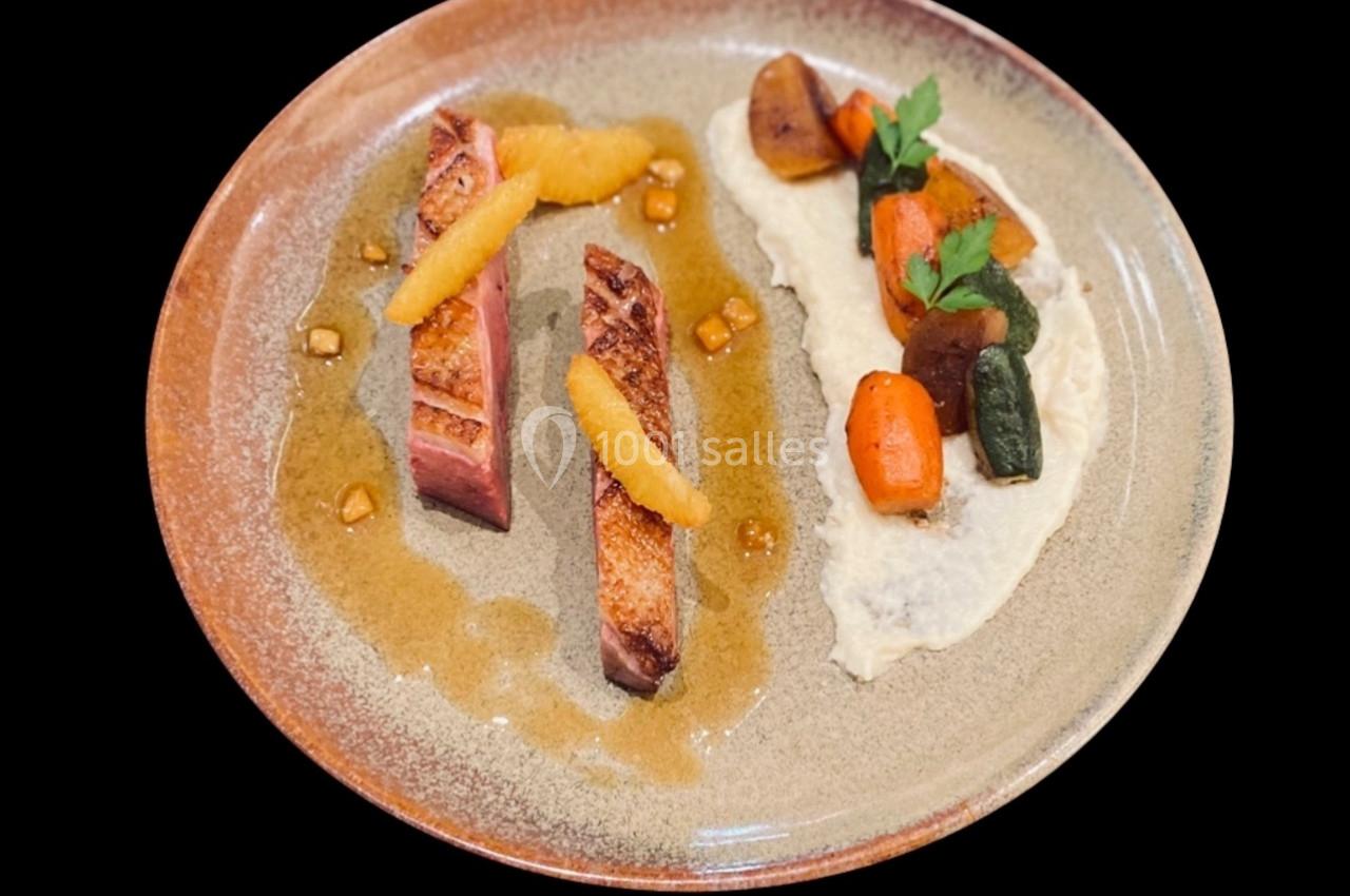 Assiette gastronomique avec viande grillée, purée, légumes rôtis et sauce disposés de manière élégante.