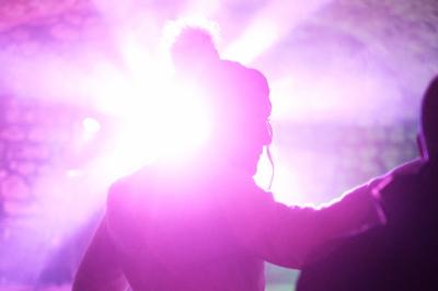 Corset blanc en dentelle et satin éclairé par des lumières vertes et violettes dans un environnement sombre.