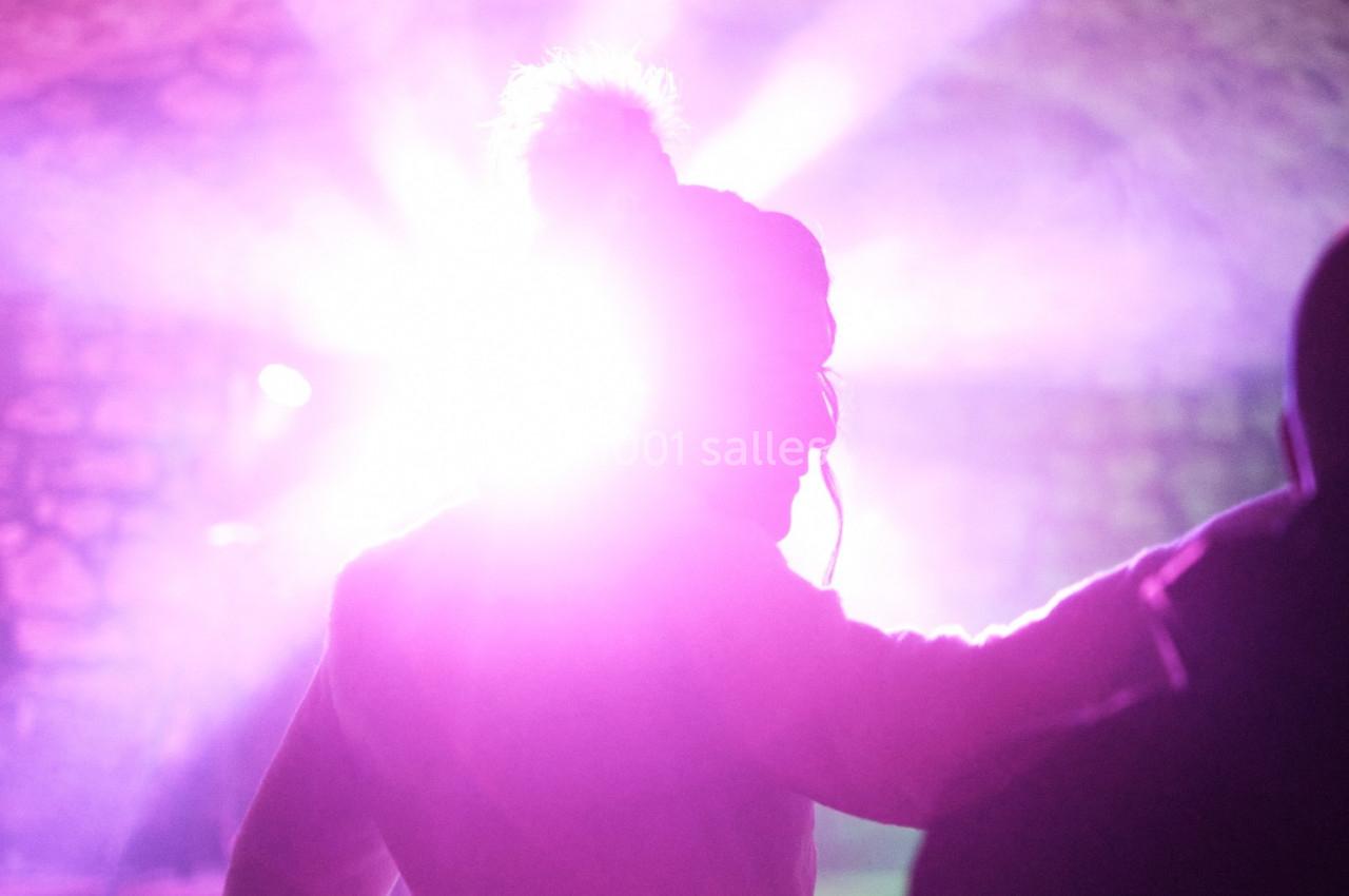 Silhouette d'une personne de profil dans une lumière rose intense, avec un mur en arrière-plan flou.