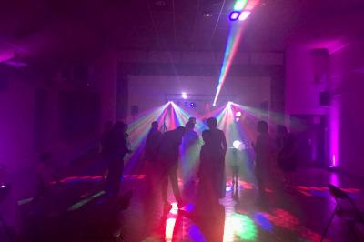 Corset blanc en dentelle et satin éclairé par des lumières vertes et violettes dans un environnement sombre.