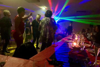 Corset blanc en dentelle et satin éclairé par des lumières vertes et violettes dans un environnement sombre.