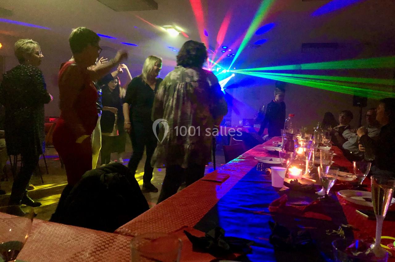 Des personnes dansent sous des lumières colorées lors d'une soirée, avec une table dressée en premier plan.