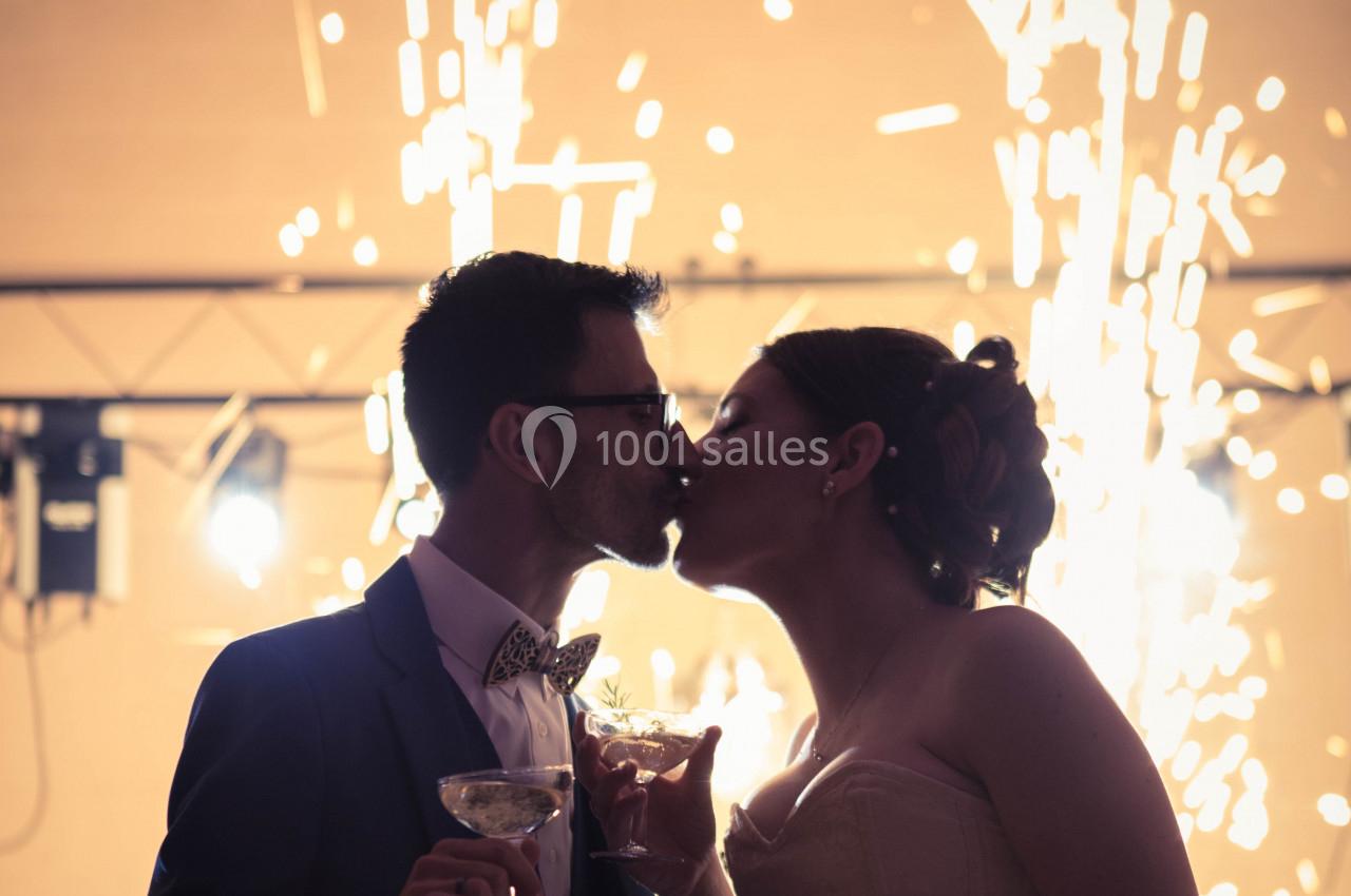 Un couple s'embrasse lors d'une célébration, des étincelles lumineuses illuminent l'arrière-plan.
