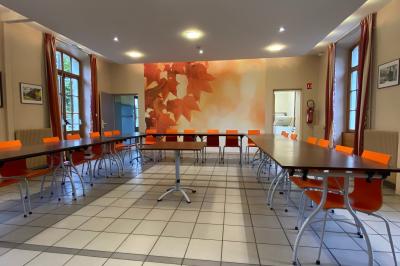 Miniature Location salle Sergenaux (Jura) - La Maison des Etangs #3 Salle de réunion lumineuse avec tables disposées en U et chaises orange, entourée de grandes fenêtres.