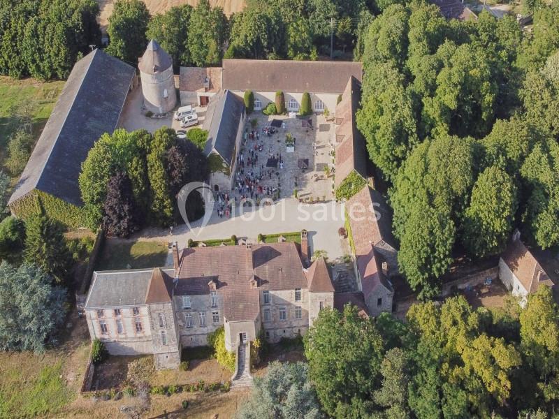 Vue aérienne d'un domaine historique avec bâtiments en pierre, cour centrale et espaces verts environnants.