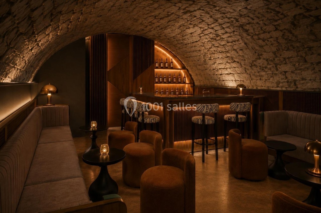 Bar élégant sous une voûte en pierre, avec éclairage tamisé, tabourets, tables basses et banquettes rembourrées.