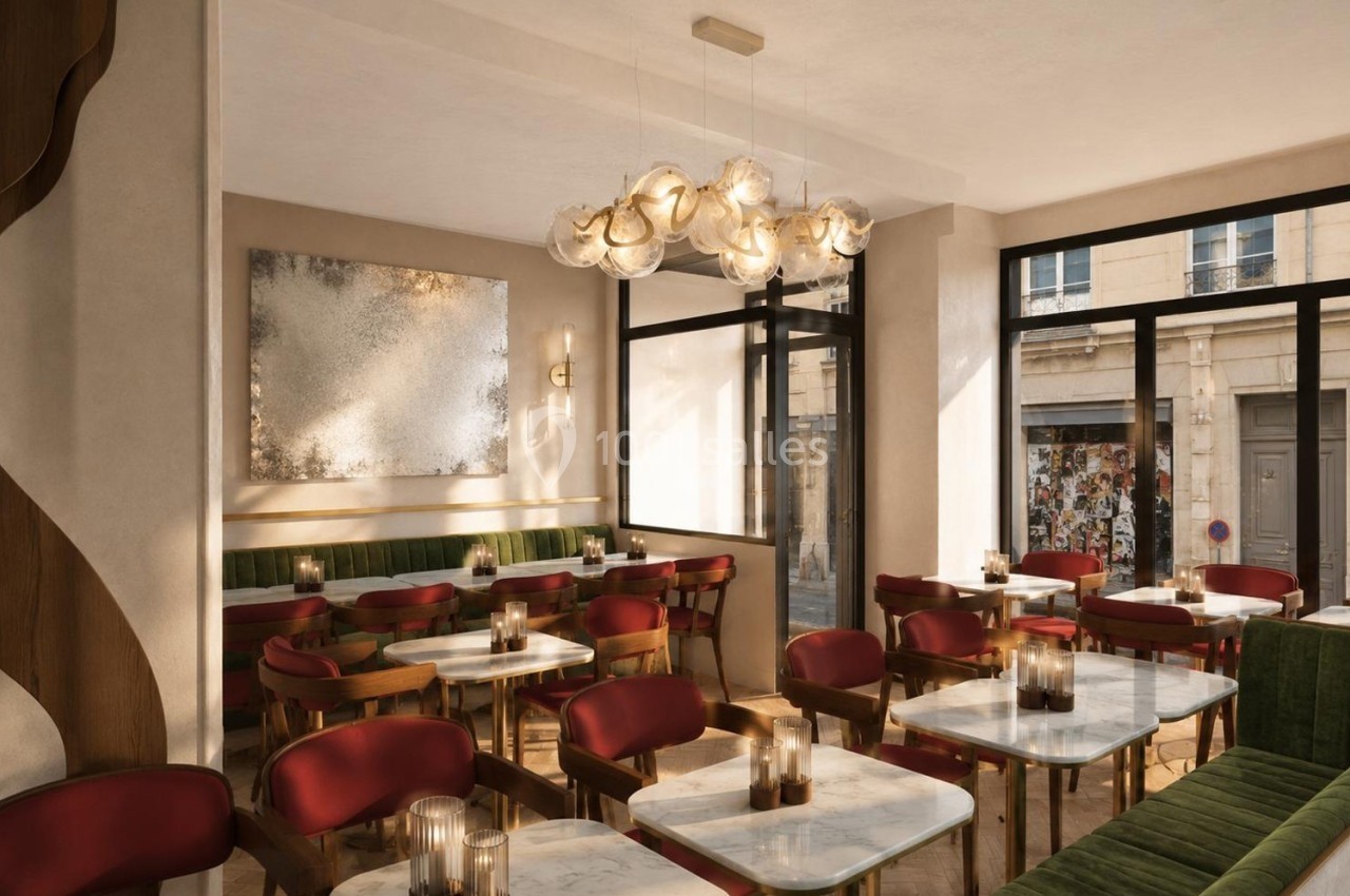 Salle de restaurant lumineuse avec tables en marbre, chaises rouges, banquettes vertes et suspension design.