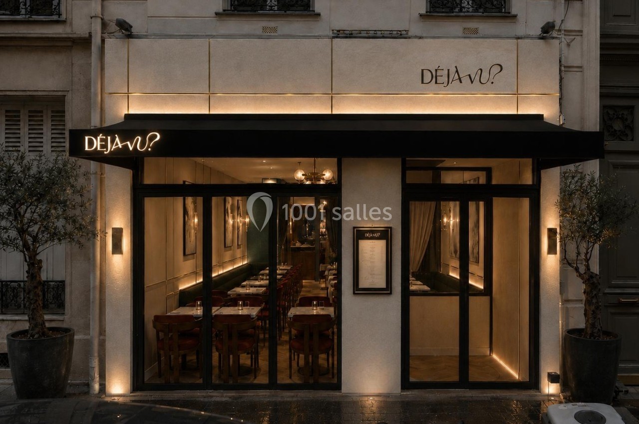 Façade d'un restaurant avec une devanture vitrée, un auvent noir et des tables visibles à l'intérieur.