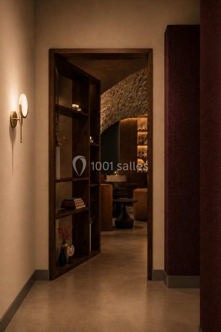 Vue d'un couloir éclairé menant à une pièce avec des étagères en bois et un espace de détente faiblement éclairé.