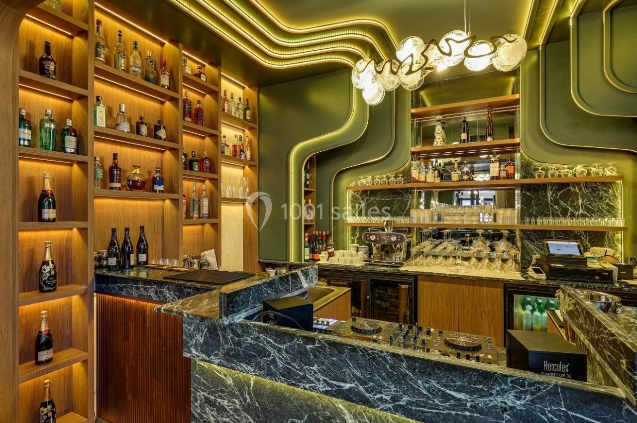 Intérieur d'un bar moderne avec comptoir en marbre, étagères illuminées de bouteilles et éclairage design.
