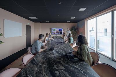 Terrasse moderne avec mobilier extérieur, vue sur une ville au coucher du soleil et ciel aux teintes orangées.