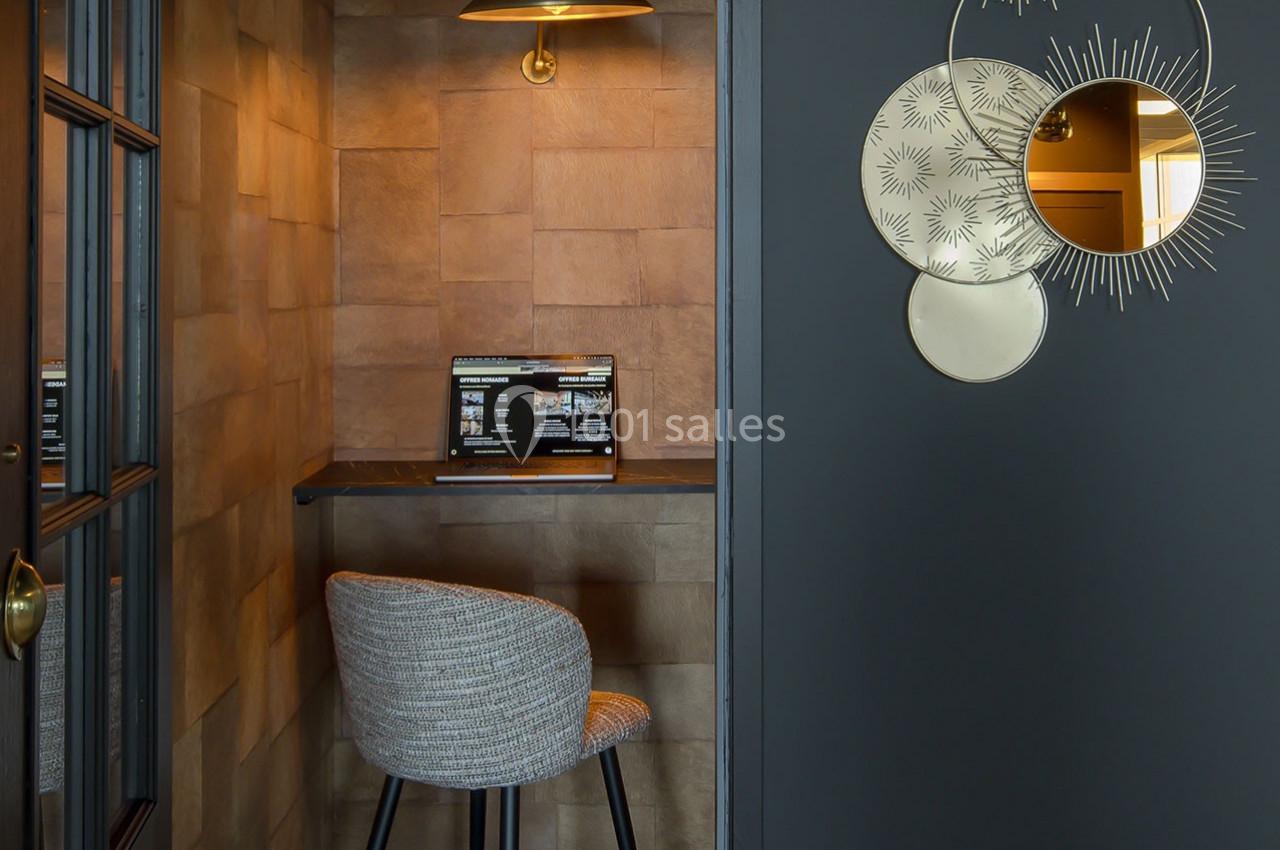 Coin bureau avec chaise rembourrée, tablette en bois, ordinateur portable et lampe suspendue, décoré de miroirs muraux.