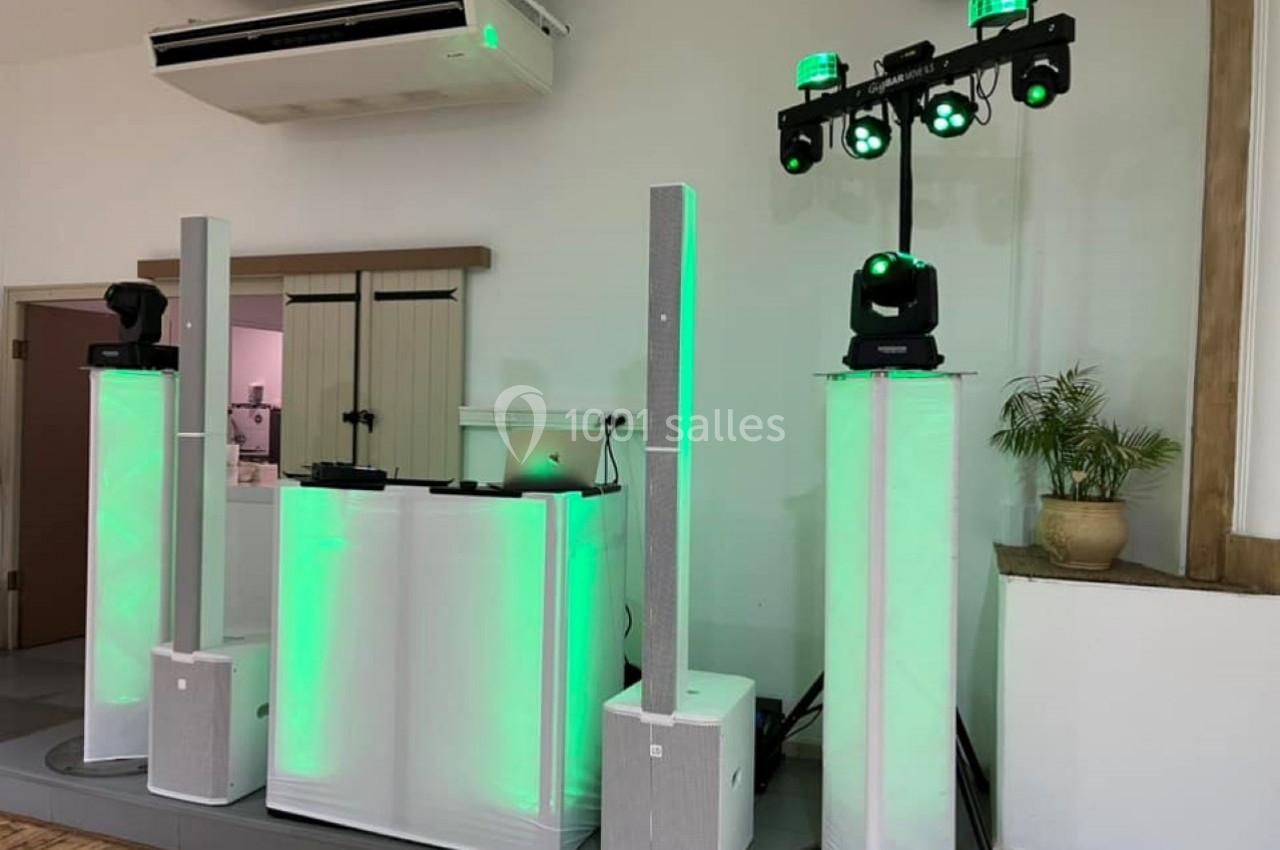 Équipement de sonorisation et éclairage avec lumières vertes installé dans une salle intérieure.