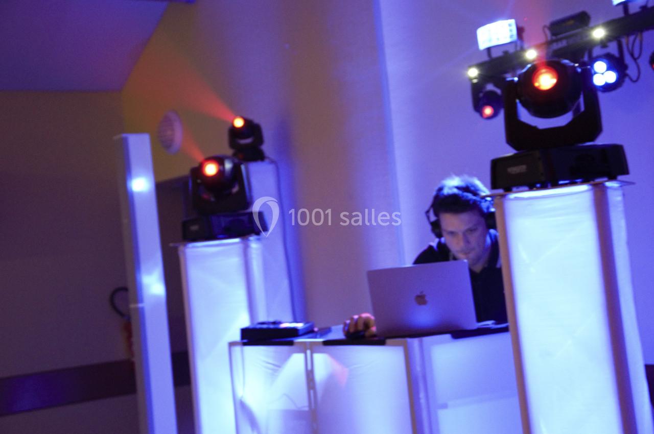 Un DJ mixe sur un ordinateur portable entouré de lumières colorées et d'équipements d'éclairage.