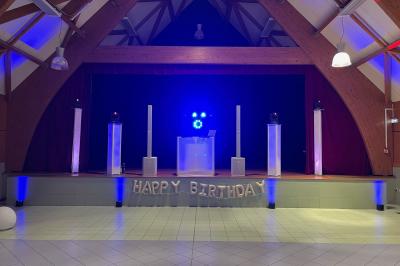 Miniature DJ Coulogne (Pas-de-Calais) - GreG évènements #11 Un DJ mixe sur un ordinateur portable, entouré de lumières colorées dans un décor en bois avec des bouées suspendues.