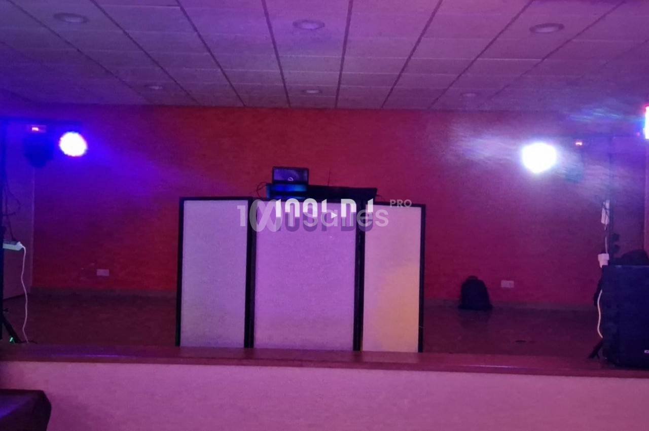 Installation de matériel de sonorisation et éclairage coloré dans une salle avec un fond de mur rouge.