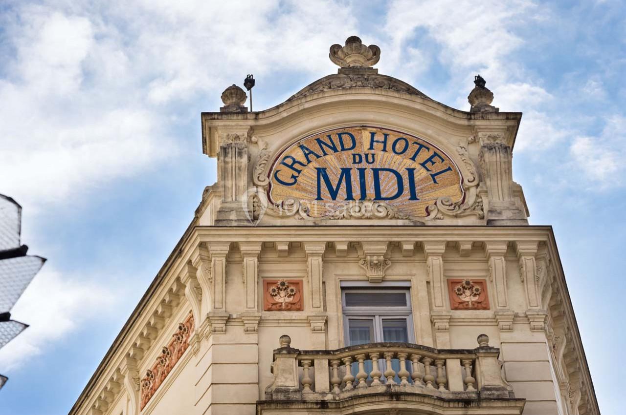 Façade d'un bâtiment ancien avec une enseigne ’Grand Hôtel du Midi’ et des détails architecturaux ornés.