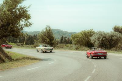 Voiture décapotable rouge garée dans un champ de lavande sous un ciel dégagé.