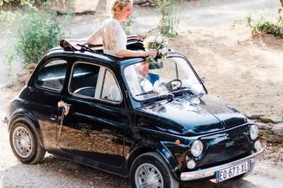 Voiture décapotable classique beige stationnée sur une allée gravillonnée entourée de haies vertes.