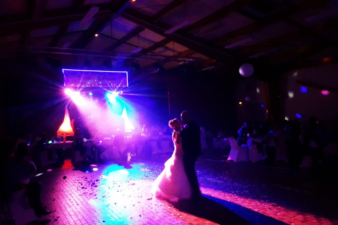 Un couple danse sur une piste éclairée par des lumières colorées lors d'une réception en soirée.