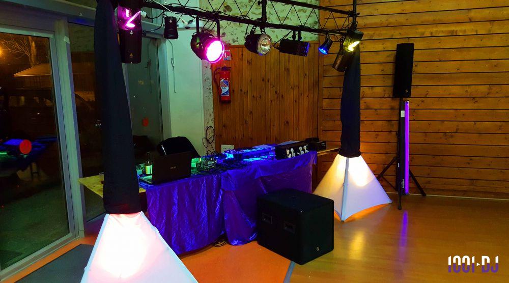 Équipement de sonorisation et éclairage coloré installé dans une salle avec murs en bois et baie vitrée.