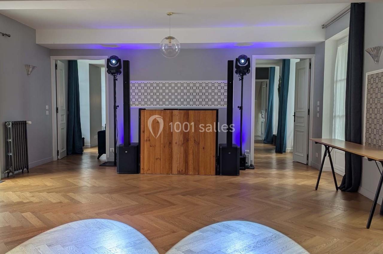 Salle lumineuse avec parquet en bois, équipement audio et éclairage coloré installé devant un mur décoratif.