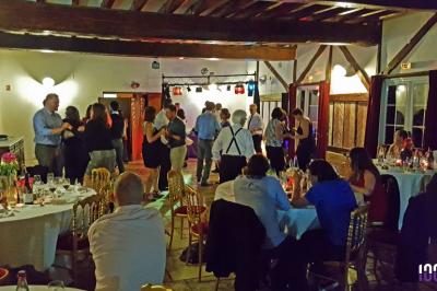 Salle de réception décorée avec des tables rondes, nappes blanches, chaises transparentes et guirlandes lumineuses.