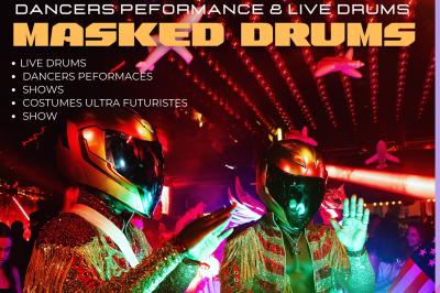 Personne portant un costume élaboré avec des ailes et un masque argenté, dans un décor intérieur faiblement éclairé.