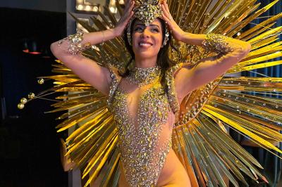 Personne portant un costume élaboré avec des ailes et un masque argenté, dans un décor intérieur faiblement éclairé.