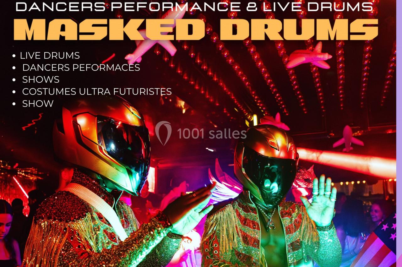 Deux artistes en costumes futuristes et casques dorés jouent de la musique dans une ambiance festive et lumineuse.