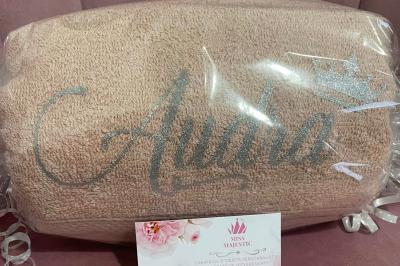 Flûte personnalisée avec le prénom ’Marion’ et bougie marquée ’50 ans’, posées sur une table devant un fond rose.