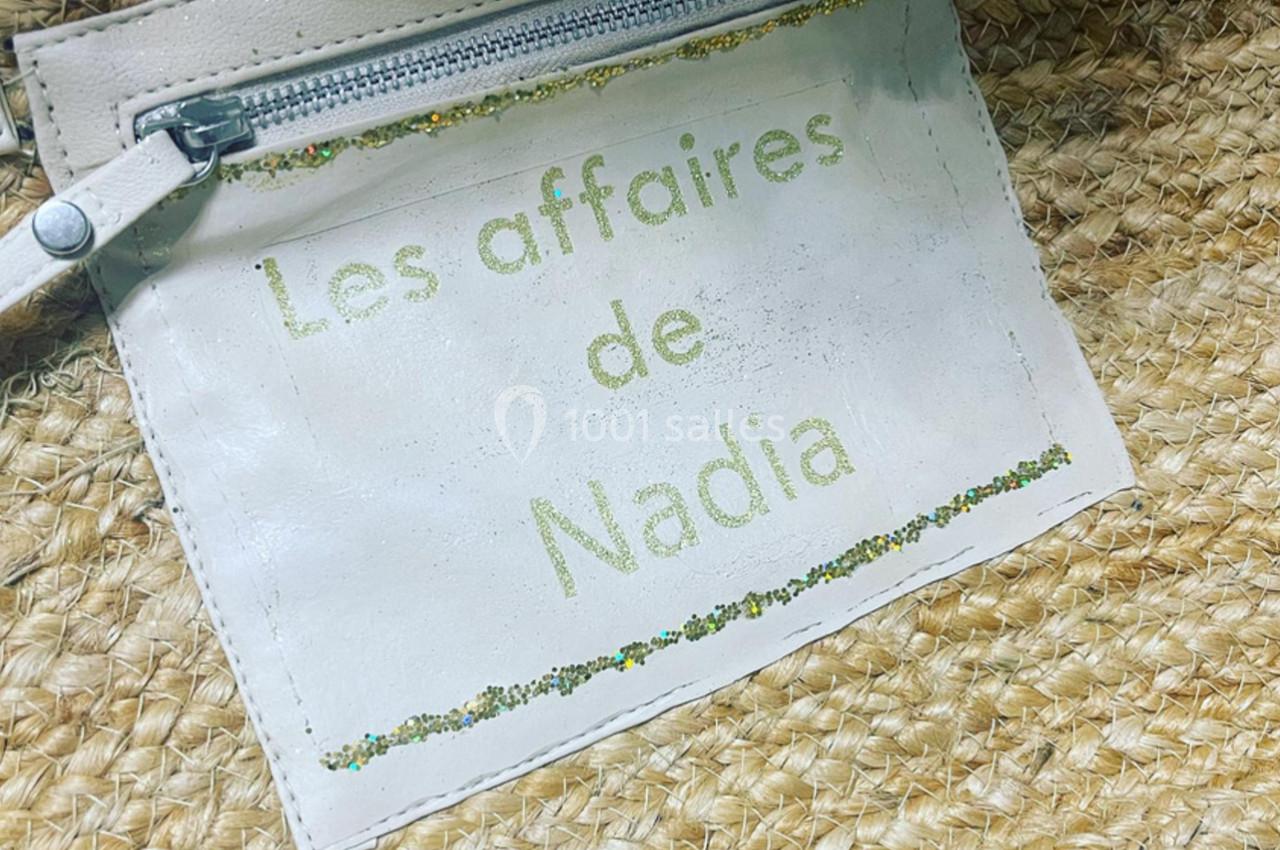 Étiquette en cuir blanc avec une fermeture éclair, portant l'inscription ’Les affaires de Nadia’, sur un sac en paille…
