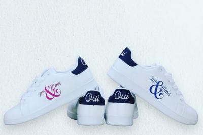 Flûte personnalisée avec le prénom ’Marion’ et bougie marquée ’50 ans’, posées sur une table devant un fond rose.