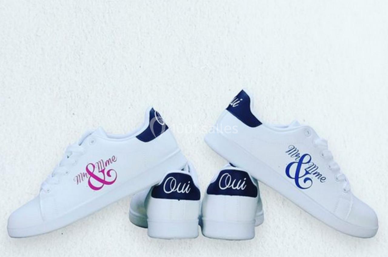 Chaussures blanches personnalisées avec inscriptions ’Mr & Mme’ et ’Oui’ sur un fond blanc.