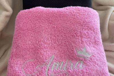 Flûte personnalisée avec le prénom ’Marion’ et bougie marquée ’50 ans’, posées sur une table devant un fond rose.