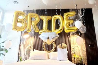 Flûte personnalisée avec le prénom ’Marion’ et bougie marquée ’50 ans’, posées sur une table devant un fond rose.