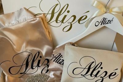 Flûte personnalisée avec le prénom ’Marion’ et bougie marquée ’50 ans’, posées sur une table devant un fond rose.