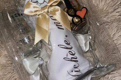 Flûte personnalisée avec le prénom ’Marion’ et bougie marquée ’50 ans’, posées sur une table devant un fond rose.